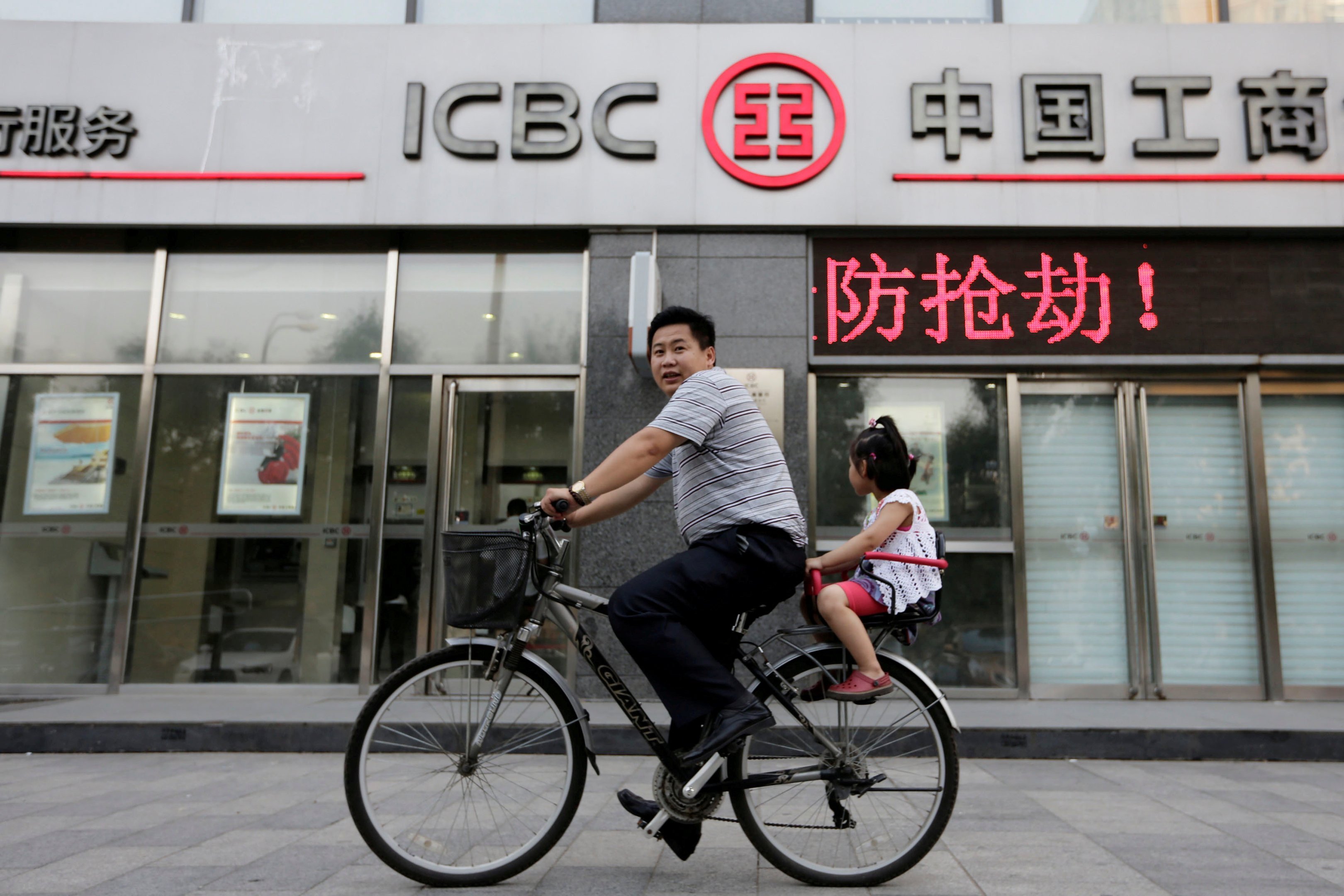 Homem e filha andam de bicicleta na frente de uma agência do banco ICBC, em Pequim, dia 26/06/2013
