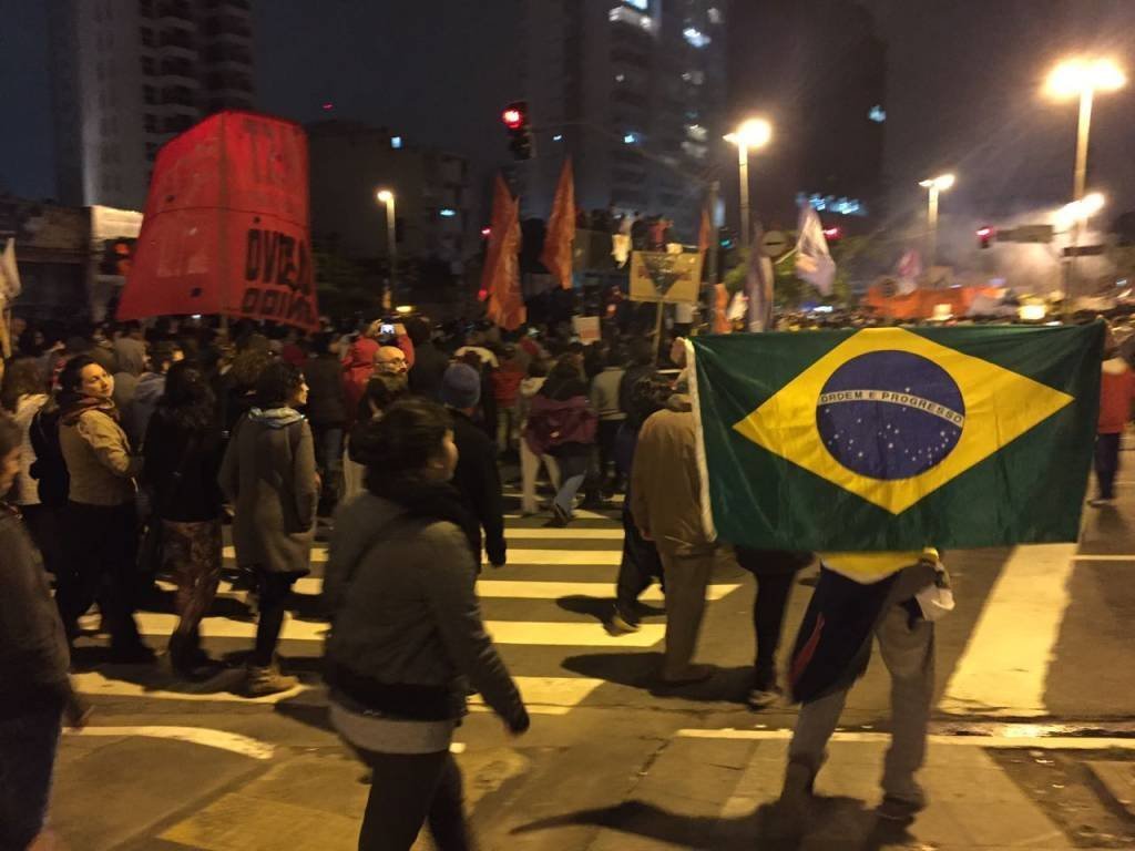 Manifestante segura bandeira do Brasil em protesto contra reformas em 28/04