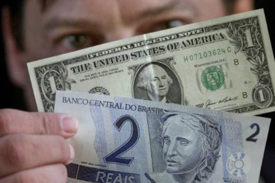 Câmbio: homem segura notas de dólar e real