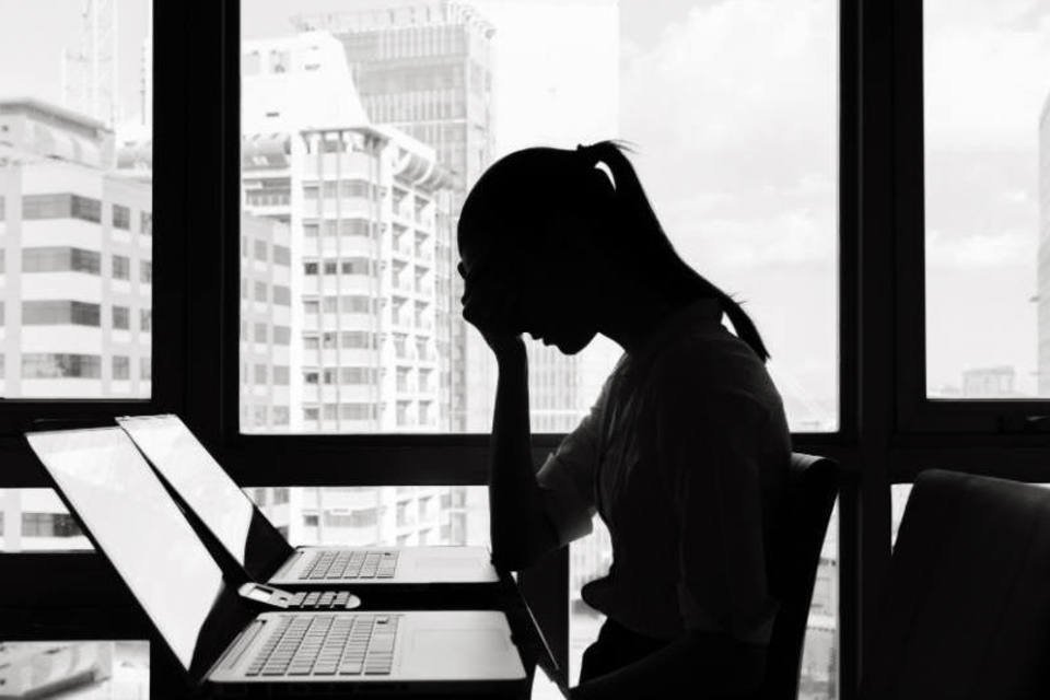 Mulher deprimida na frente de computador em escritório (demissão, falência)