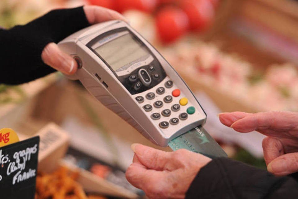 Mulher faz o pagamento de suas contas com um cartão de crédito em uma loja de frutas no subúrbio de Paris, na França