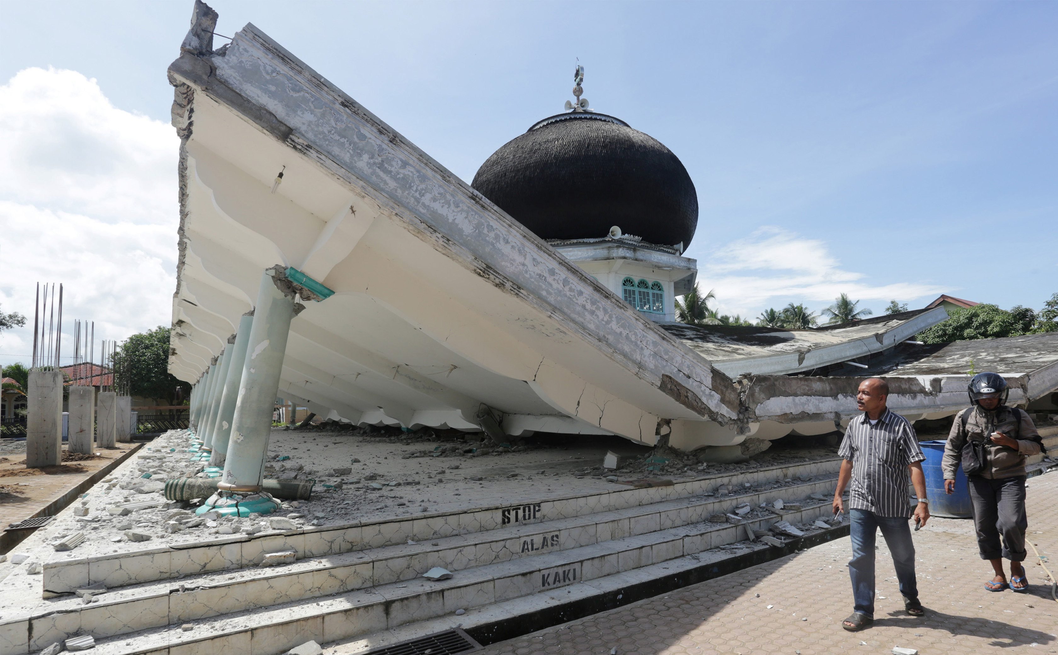 Pessoas andam próximas a mesquita destruída após terremoto na Indonésia no dia 07/12/2016