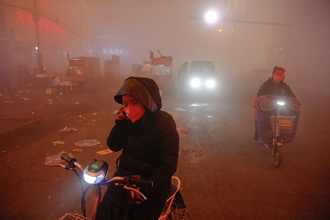 Em Shengfang, província de Hebei, na China, pessoas enfrentam poluição intensa em um dia extremamente poluído com alerta vermelho.