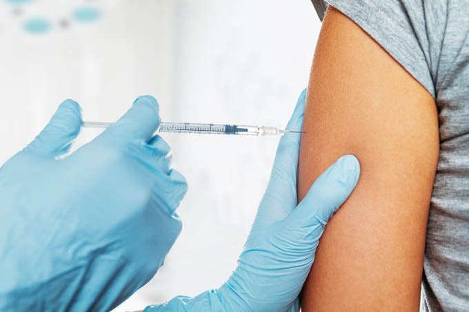 Pessoa tomando uma vacina no braço