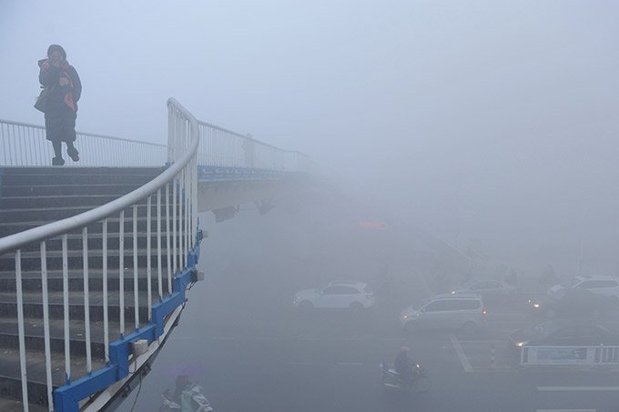Mulher atravessa ponte na China em dia poluído em 03.01.2017.