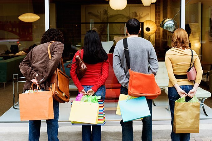 Pessoas com sacolas olham vitrine de loja