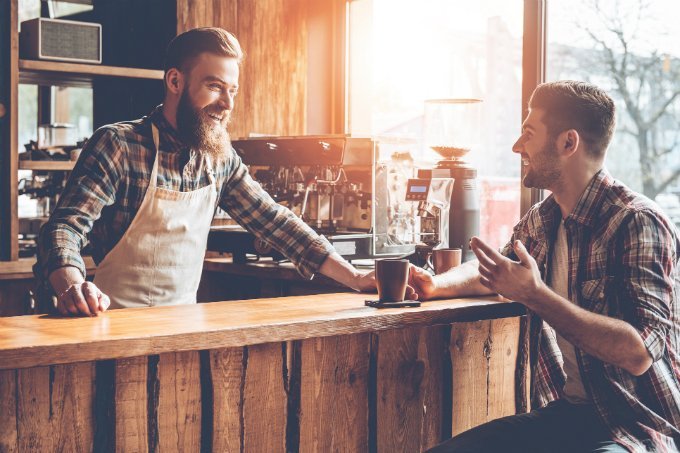 Empreendedor conversa com cliente em balcão de cafeteria