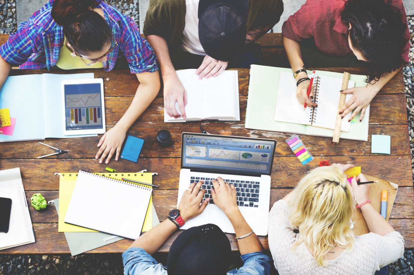 Empreendedores usam computadores, cadernos e post-its em mesa de trabalho: planejamento, reunião, startups