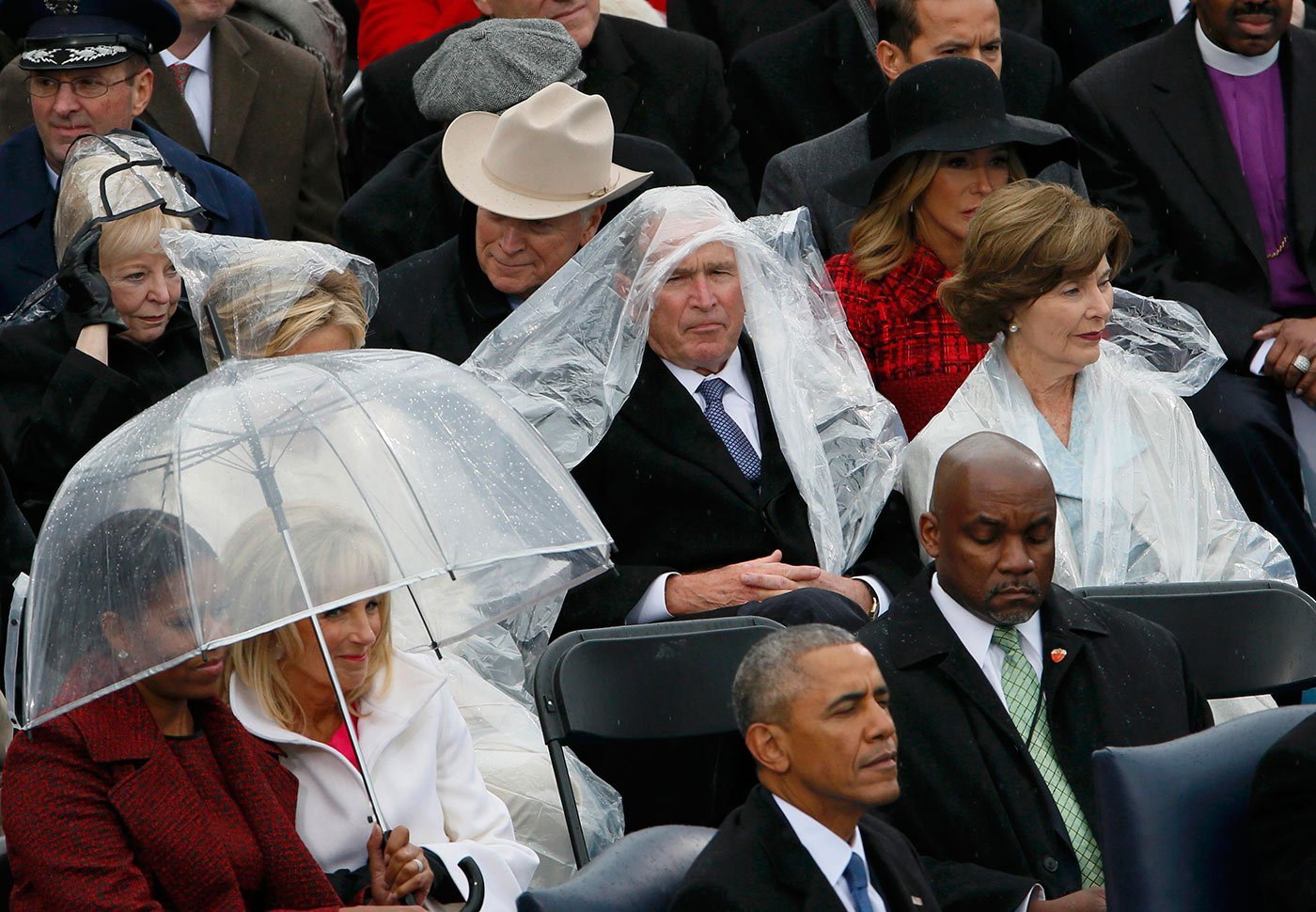 Enquanto Trump discursa, Barack Obama aparece de olhos quase fechados, George W. Bush tenta se proteger da chuva, assim como Michelle Obama e Jill Biden, mulher do ex-vice-presidente Joe Biden (Rick Wilking/ Reuters)