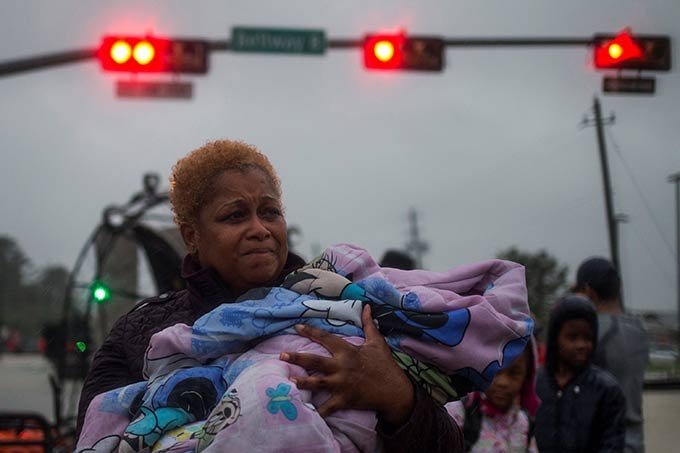 Mulher segurando criança no colo foge das enchentes em Houston provocadas pelo furacão Harvey nos Estados Unidos.