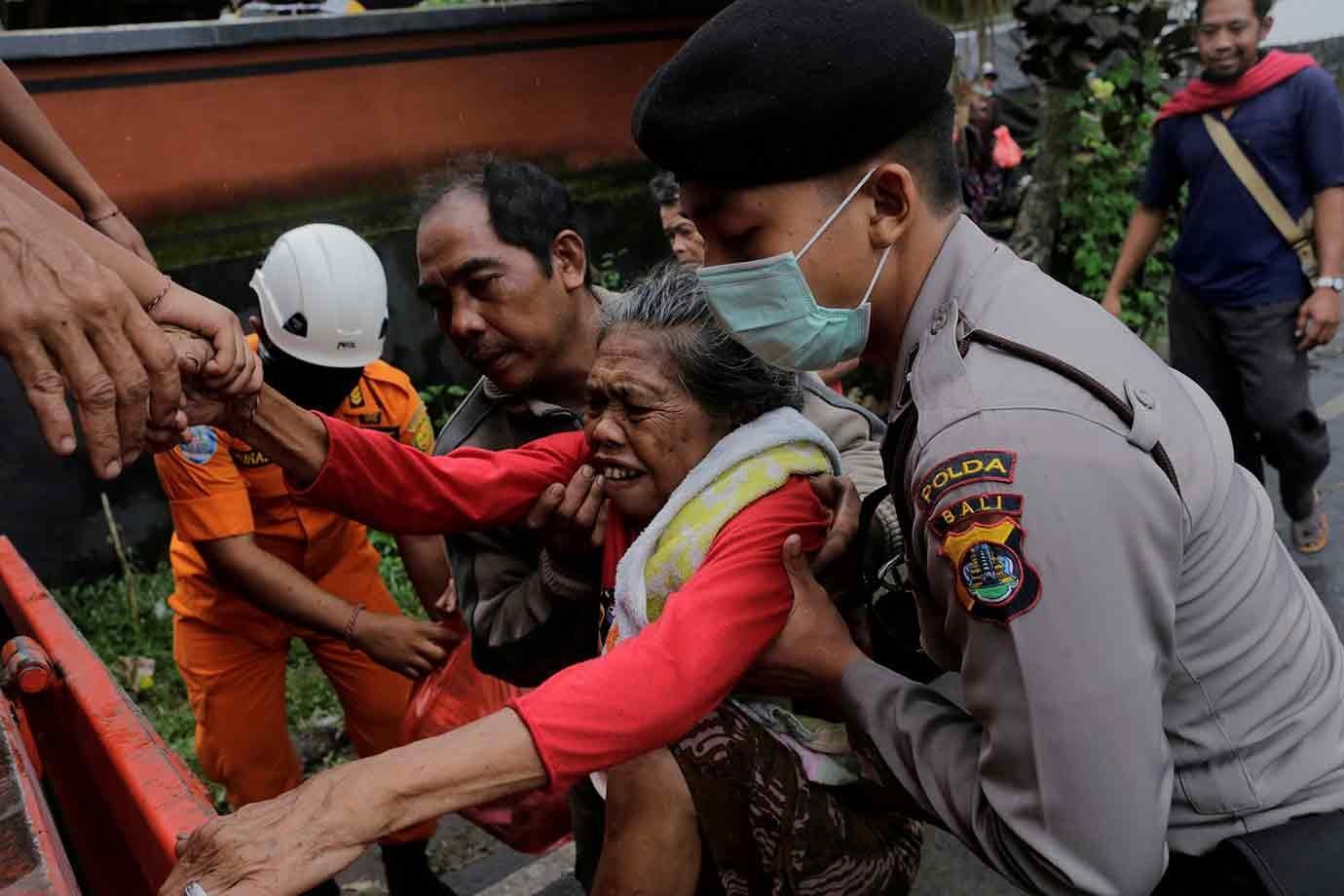 Bombeiros ajudam a retirar uma senhora da área de evacuação em Bali, em 28/11/2017.