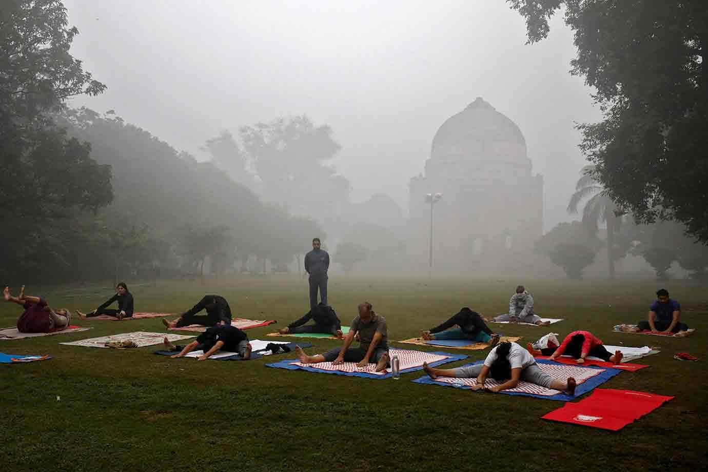 Pessoas se exercitam em um parque em Nova Deli em uma manhã poluída
