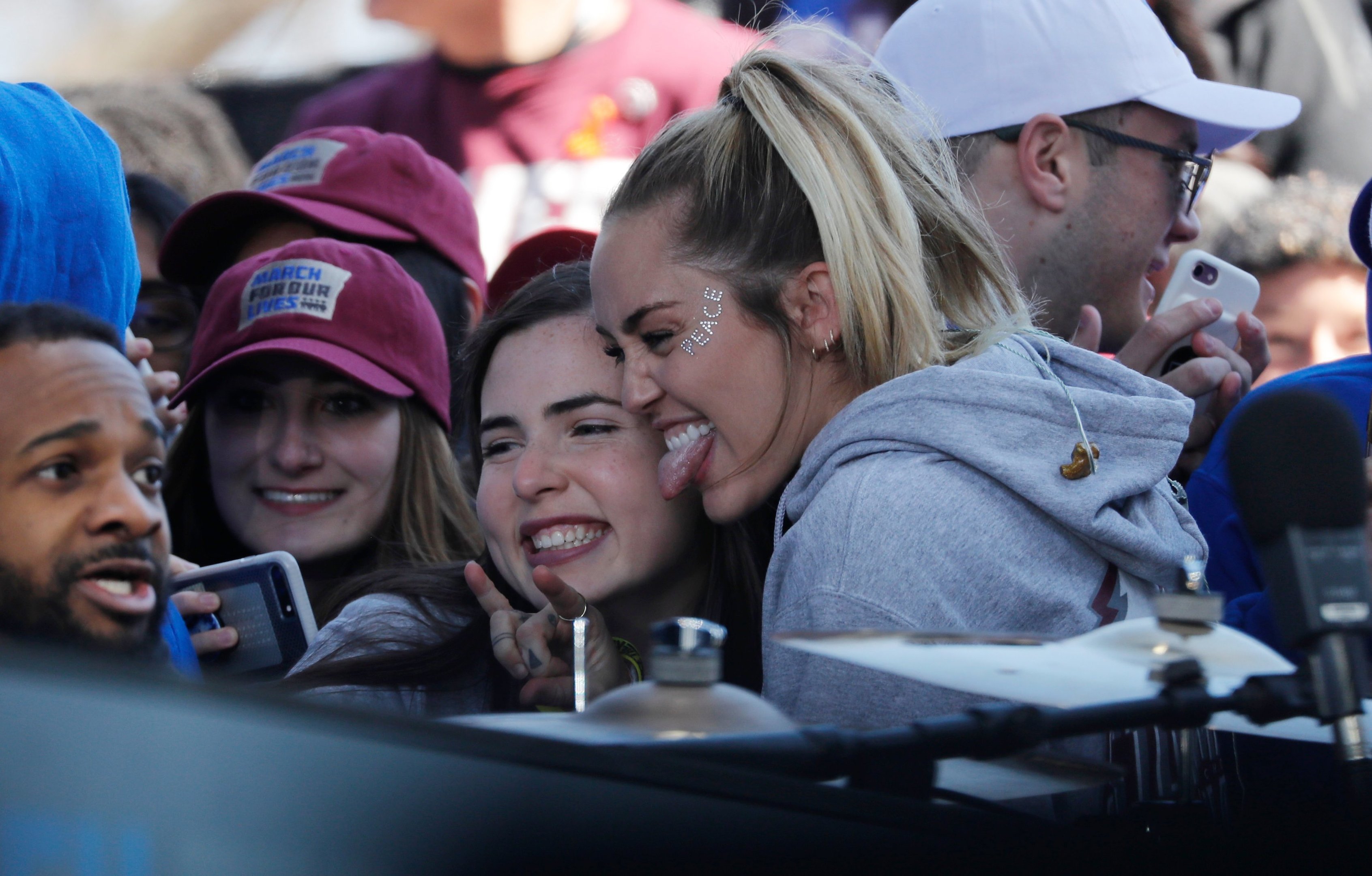 Singer Miley Cyrus poses with students and gun control advocates as they hold the "March for Our Lives" event demanding gun control after recent school shootings at a rally in Washington, U.S., March 24, 2018. REUTERS/Jonathan Ernst