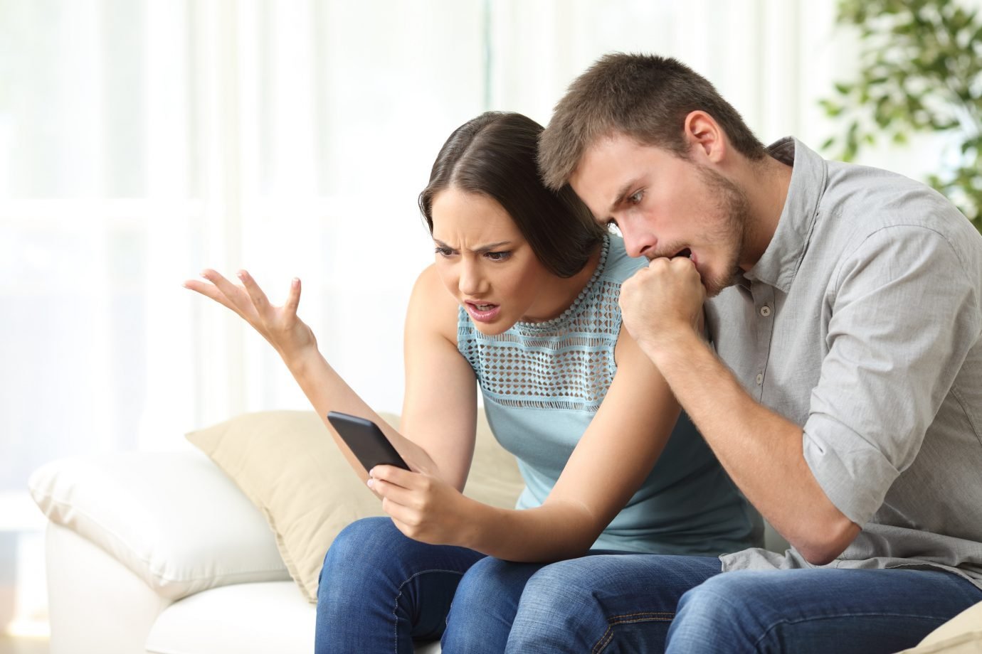 Homem e mulherem olham para celular irritados; mau atendimento