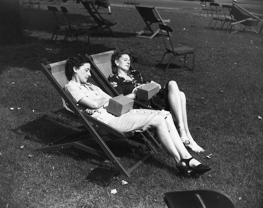 5th September 1939: A couple of lady office workers with gas-masks on their laps, sleeping peacefully in Hyde Park during their lunch hour. (Photo by David Parker/Fox Photos/Getty Images)