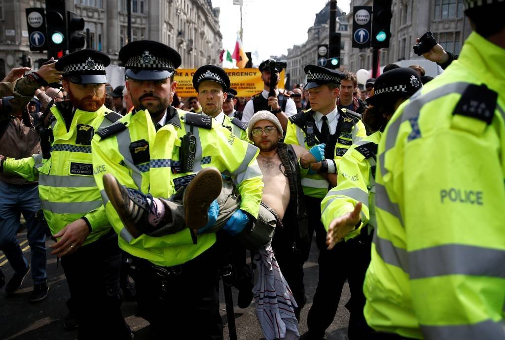 Policiais carregam manifestante que protesta em Londres contra a mudança climática.