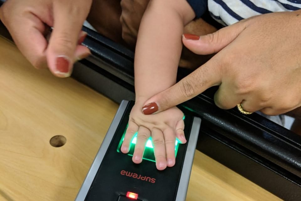 Bebê coloca palma da mão em sensor biométrico