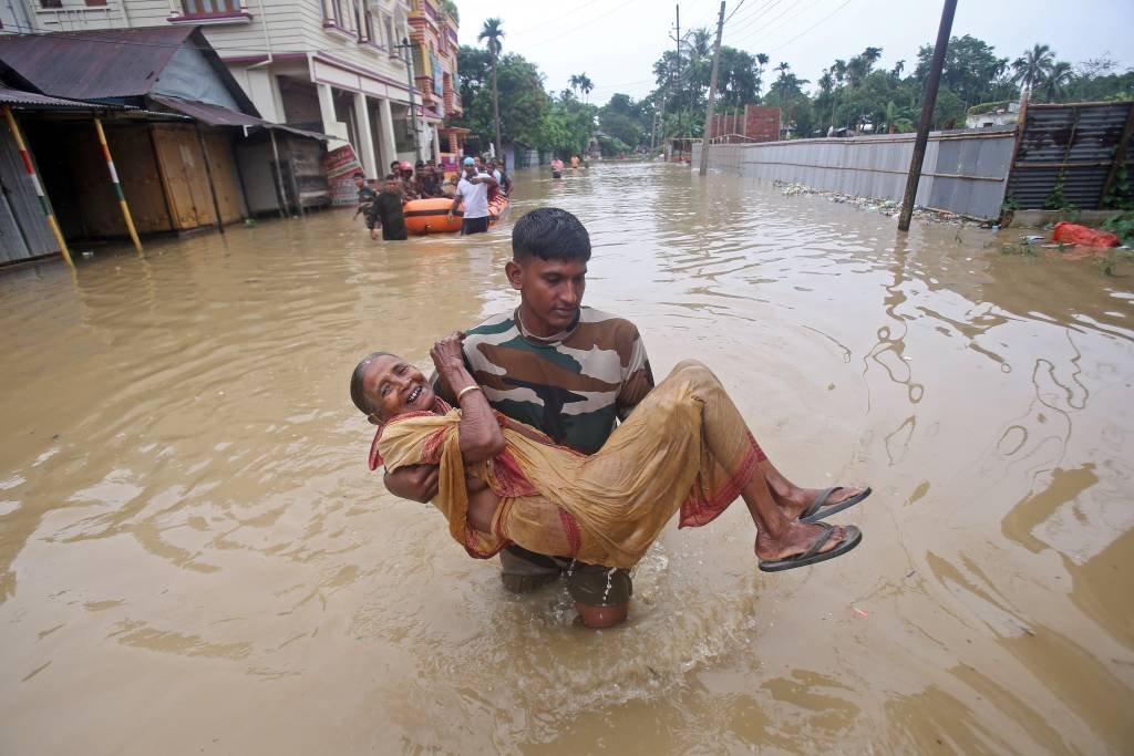 Homem carrega senhora no colo após inundações no Nepal. 16/07/2019