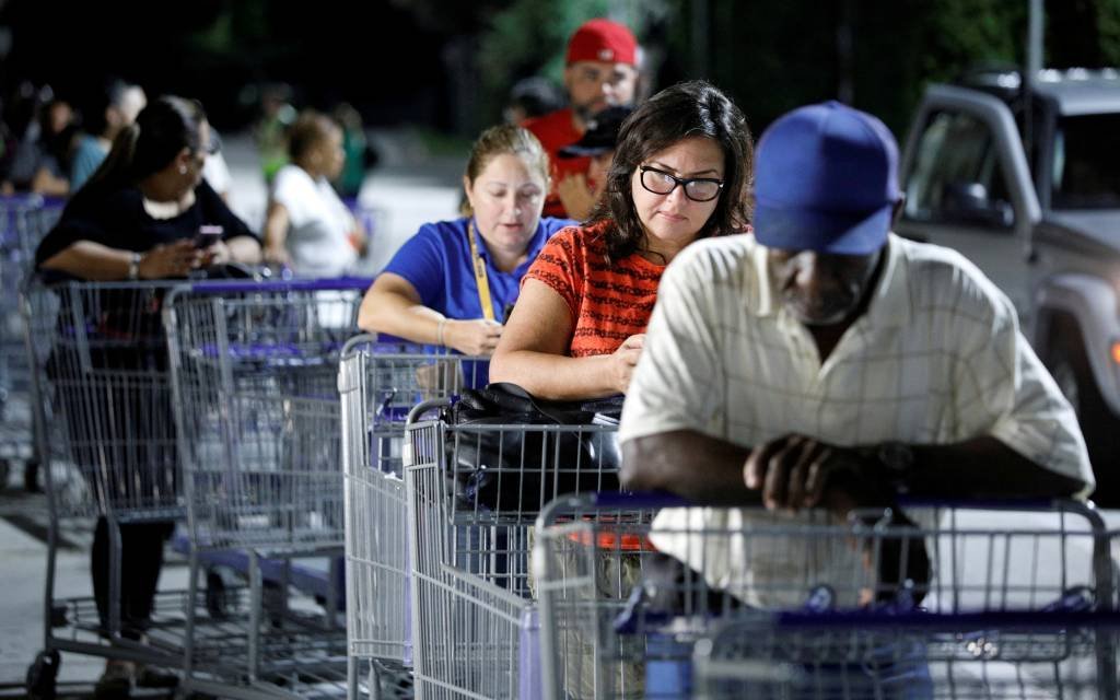 Pessoas aguardam em fila de supermercado para comprar suprimentos