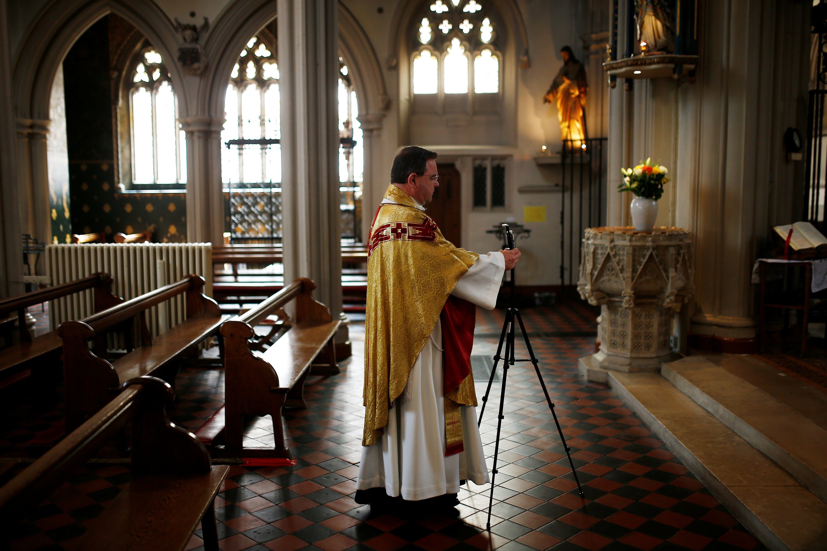 Padre arrumar celular para realizar missa de Páscoa por videoconferência, em Londres