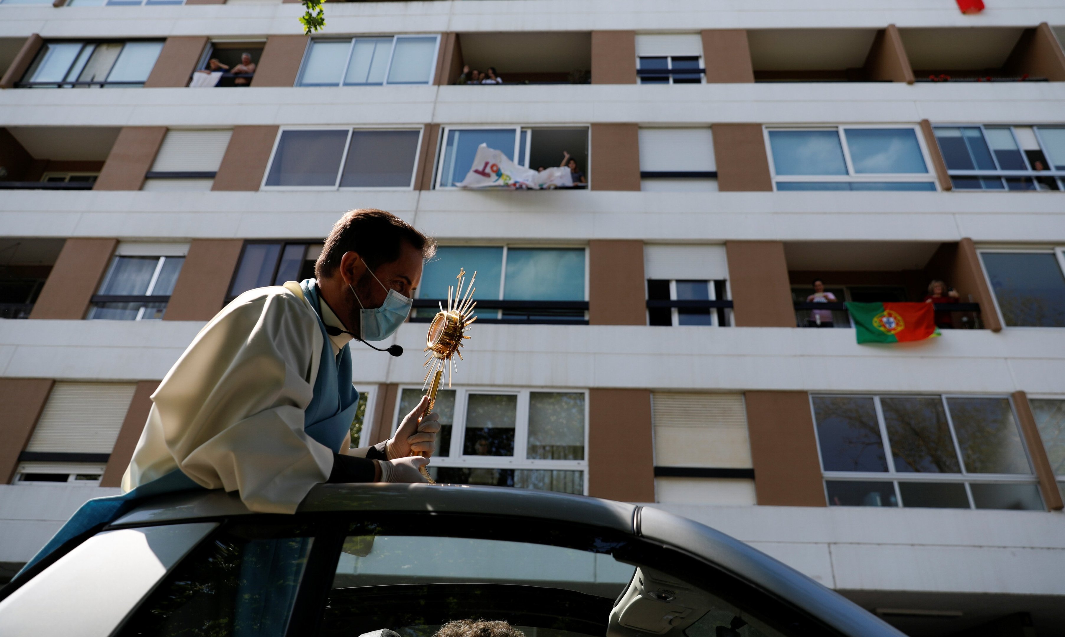 Padre faz tour de carro em bairro Oeiras, Portugal, durante o domingo de Páscoa.