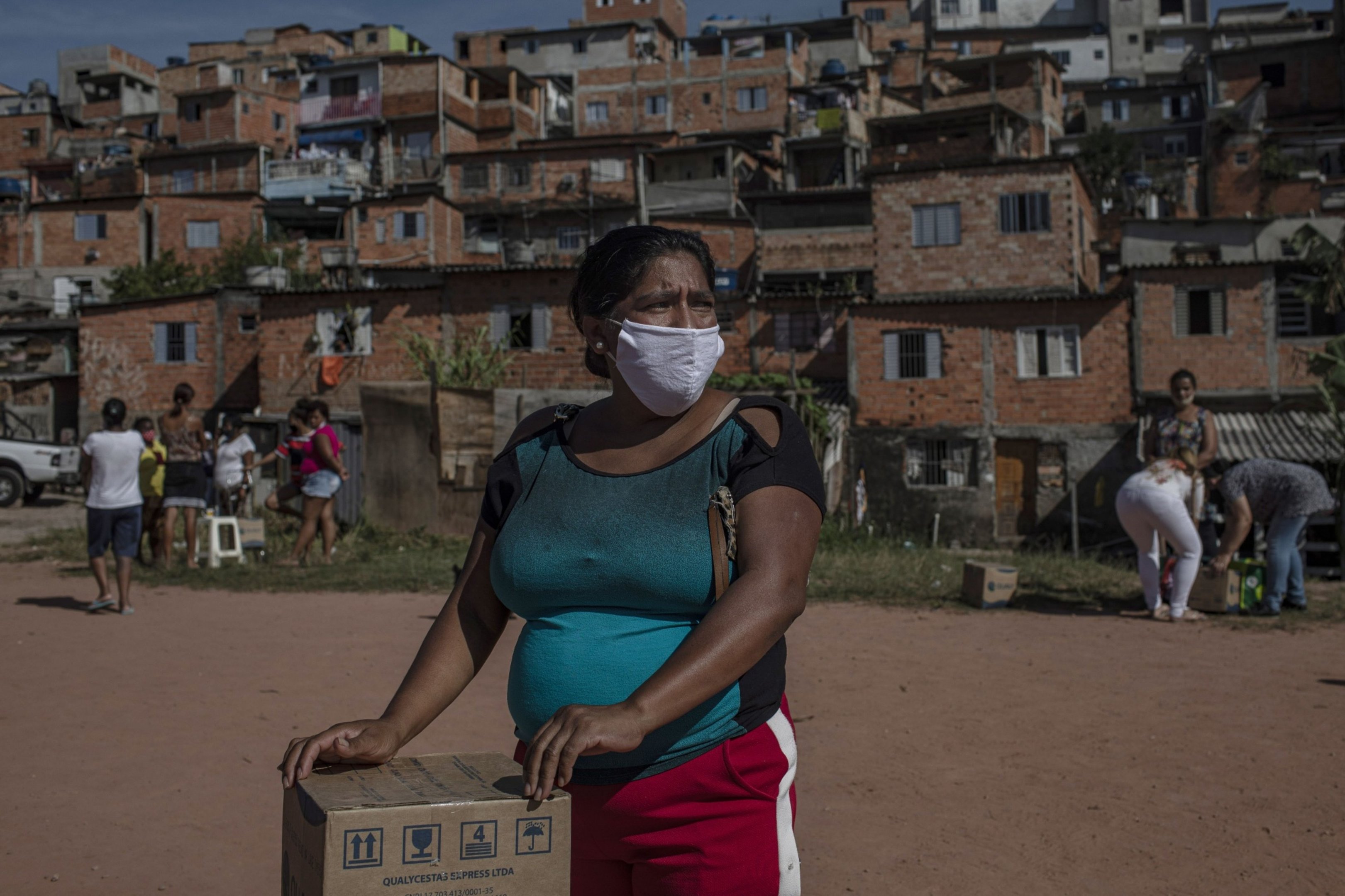 Moradora recebe uma cesta de alimentos e produtos de higiene doados na favela do Vale das Virtudes, São Paulo, 12 de junho de 2020.