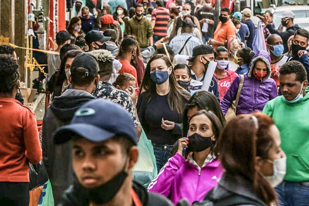 Pessoas de máscaras andam em uma rua movimentada no centro da cidade de SP. 29 de junho de 2020