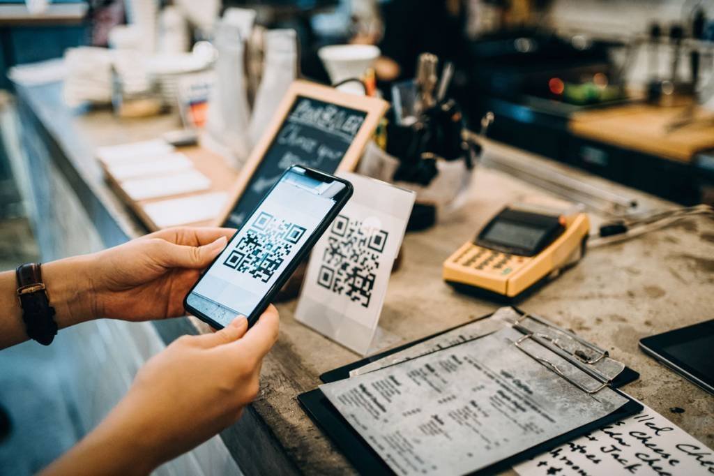 Cliente digitalizando o código QR, fazendo um pagamento sem contato rápido e fácil com seu smartphone em um café