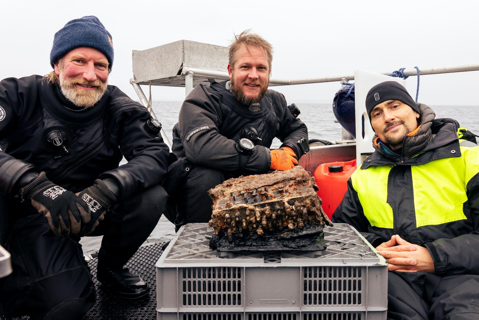 Da esquerda para a direita, os arqueólogos submarinos Christian Howe, Florian Huber and Uli Kunz posam para foto com a máquina Enigma encontrada por eles