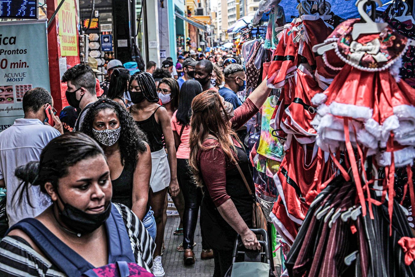 Mulher olha para roupas enquanto as pessoas caminham na popular rua comercial 25 de Março antes do Natal, em meio ao surto da doença do coronavírus (COVID-19), no centro de São Paulo, Brasil, 21 de dezembro de 2020. REUTERS / Amanda Perobelli