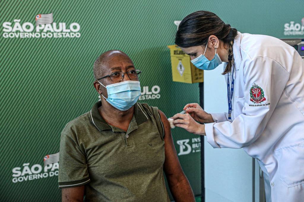 SÃO PAULO, BRASIL - 17 DE JANEIRO: A enfermeira Wilson Paes de Padua (57) recebe a vacina CoronaVac da enfermeira do Controle de Doenças e Mestre em Saúde Pública da Santa Casa de São Paulo, Jessica Pires de Camargo, 30 anos no Hospital das Clínicas da Universidade de São Paulo (USP) em 17 de janeiro de 2021 em São Paulo, Brasil. A vacina CoronaVac foi desenvolvida pelo laboratório chinês Sinovac em parceria com o Instituto Butantan. A Agência Nacional de Vigilância Sanitária (Anvisa) autorizou hoje o uso emergencial do CoronaVac e do AstraZeneca (desenvolvido pela Universidade de Oxford em parceria com a Fundação Oswaldo Cruz (Fiocruz) vacinas contra Covid-19. (Foto Rodrigo Paiva / Getty Images )