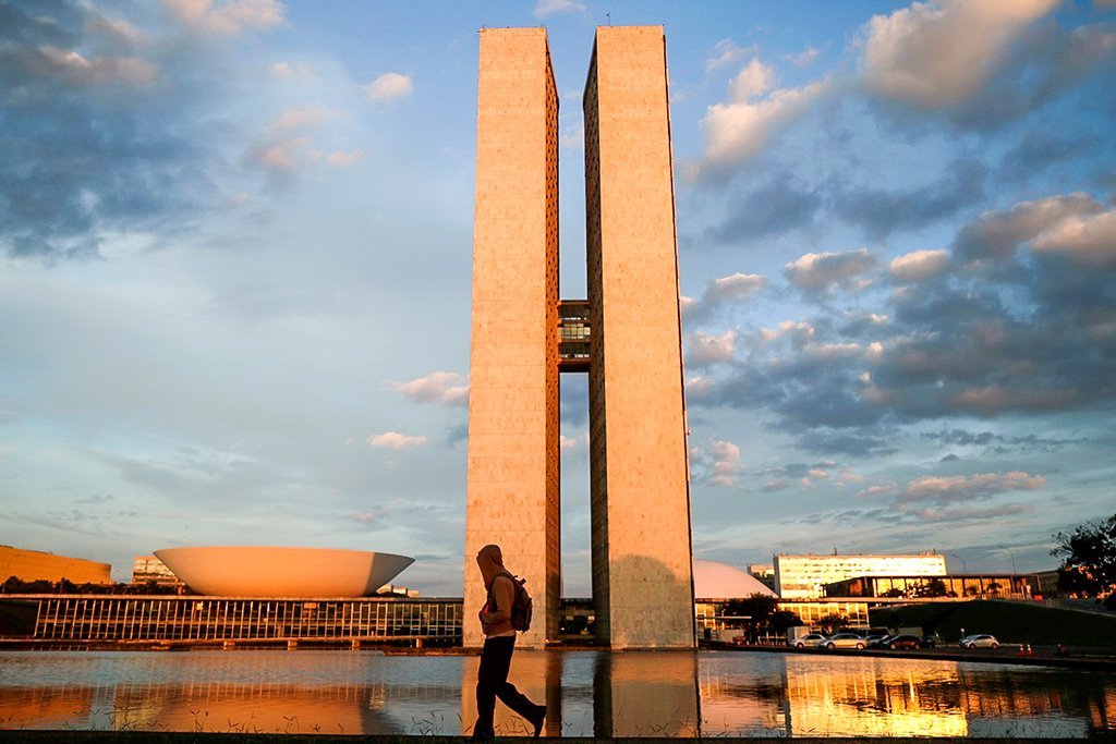 Homem caminha perto do prédio do Congresso Nacional em Brasília